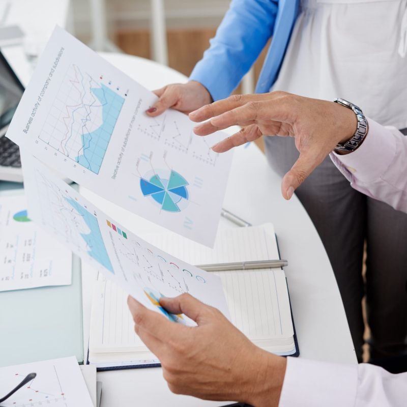 Close-up image of coworkers discussing business charts and graphs at the meeting