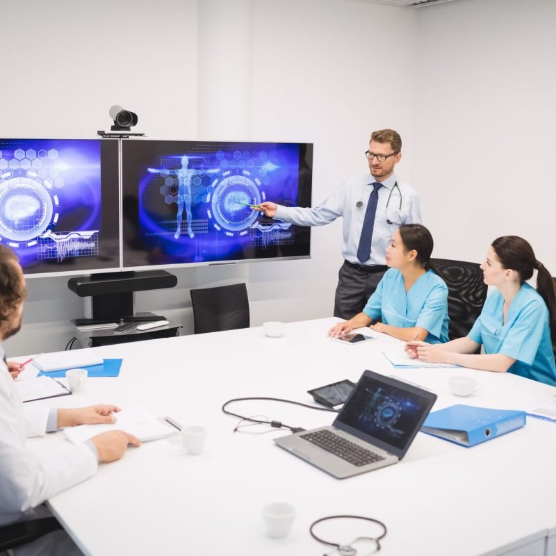 Doctor giving presentation to team of interim doctors at conference room