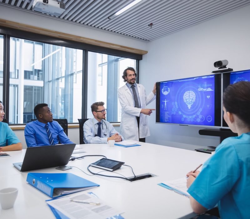 Doctor giving presentation to team of interim doctors at conference room