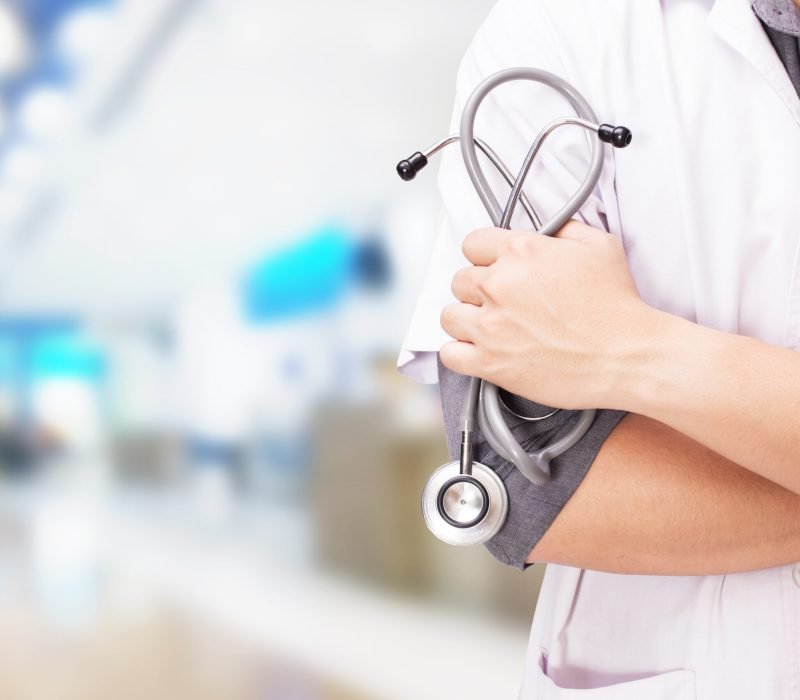 Doctor with a stethoscope in the hands and hospital background.