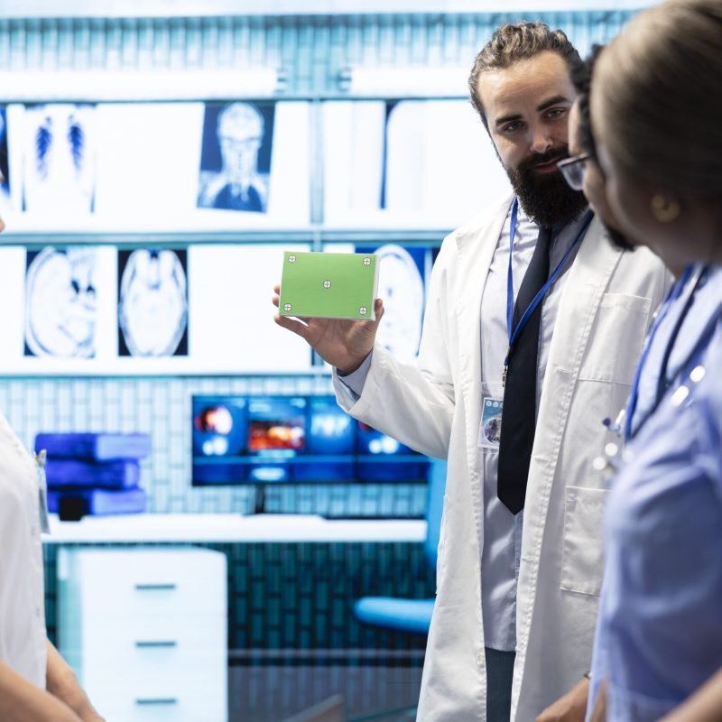 Medical expert showing a box with green screen during a meeting for diagnosis and disease prevention, conducting a detailed review of x ray scans and lab results in a clinical setting.