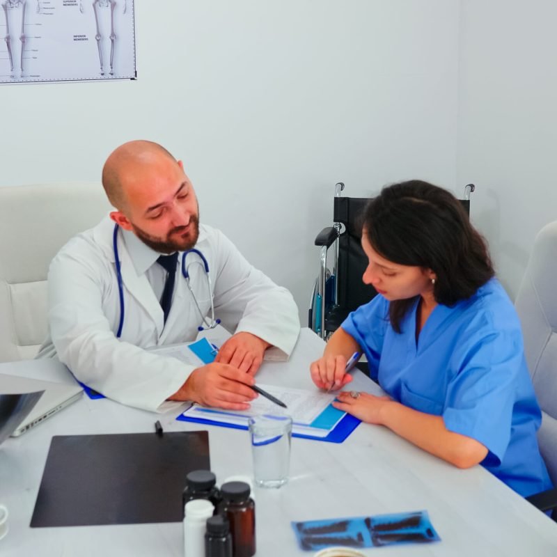 Medical expert talking with medical staff during healthcare meeting in hospital conference room explaining radiographys. Clinic therapist talking with colleagues about disease, medicine professional